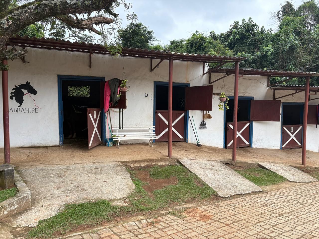 Cocheiras brancas com portas de madeira e a logo da ABRAHIPE na parede.
